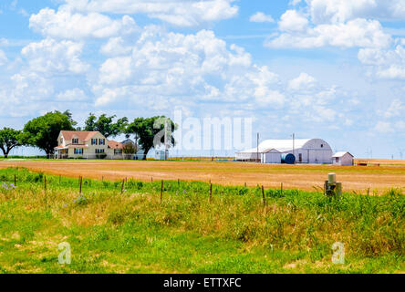 A farm with a two story house and barn, surrounded by a cut wheat field in rural Oklahoma, USA. Stock Photo