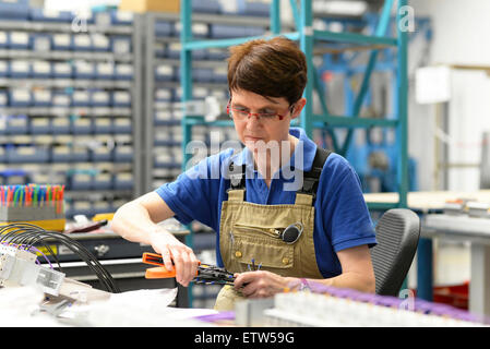 Worker assembling cables in a switchboard construction factory Stock Photo