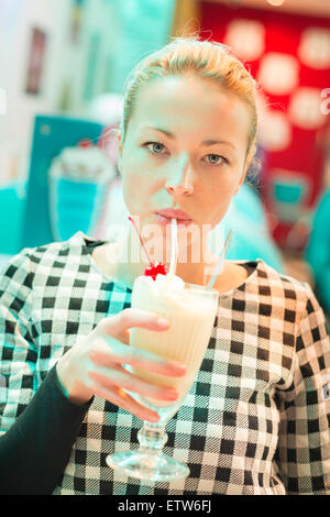 Woman drinking milk shake in diner. Stock Photo