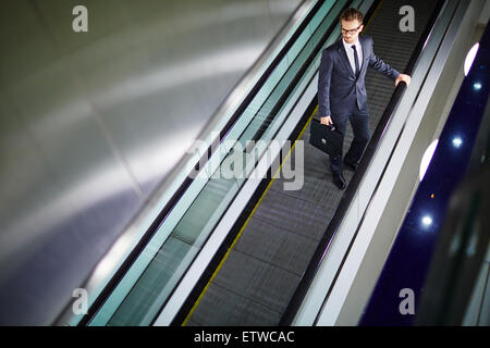 Attractive businessman moving on escalator Stock Photo