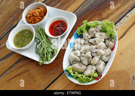 fresh oysters with side dishes on wooden desk Stock Photo