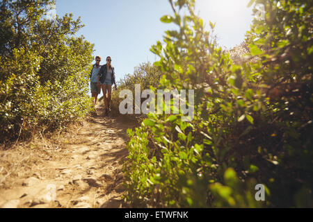 Image of two young people walking downhill. Young couple hiking on mountain on a summer day. Stock Photo