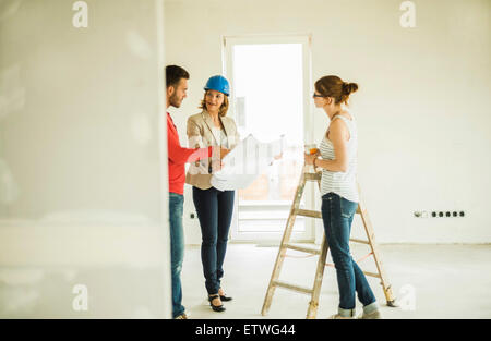 Architect showing construction plan to young couple Stock Photo