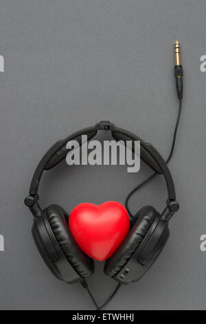 black headphones with red heart, wires and socket on gray background Stock Photo