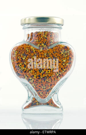 Closed lid heart shaped glass jar filled with apis honey bee natural dried fresh organic pollen grains Stock Photo