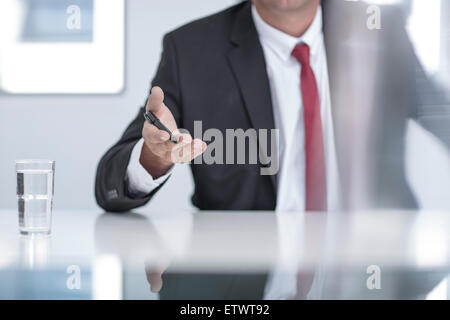 Businessman in office holding pen in hand, mid section Stock Photo