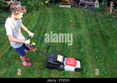 Berlin, Germany, boy mows the lawn in a garden Stock Photo