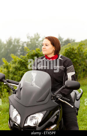 Motorcyclist sitting with view into the distance on a motorcycle Stock Photo