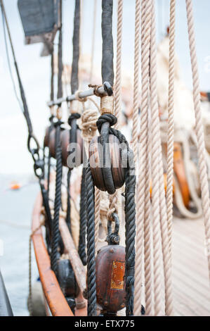 Marine ropes and tackles on the tall ship. Old wooden block with rope on the sail. Stock Photo