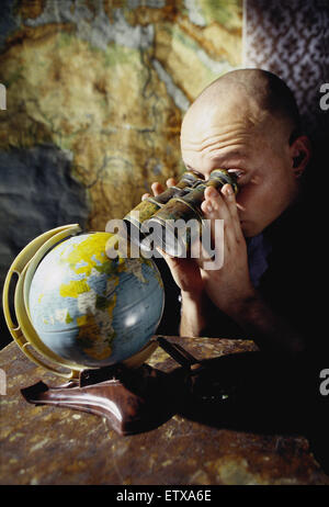 Hamburg, Germany, man looking through binoculars on a globe Stock Photo