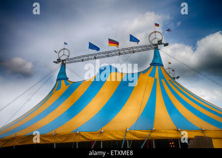 blue and yellow striped circus tent under a blue sky Stock Photo