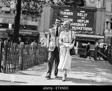 Angela Lansbury and Peter Shaw, pictured walking in Leicester Square, London 26th July 1949. The couple are in London for their Wedding Ceremony. In background, The Empire Cinema, promoting new release The Three Musketeers, starring Lana Turner, Gene Kelly, June Allyson, Van Heflin and Angela Lansbury. Stock Photo