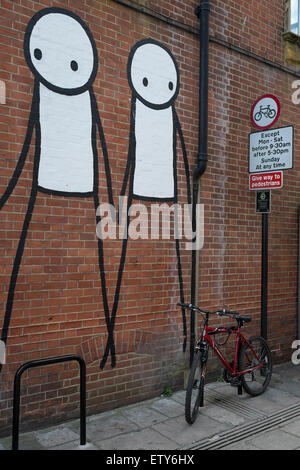 Stick men are painted on a London brick wall near a bicycle Stock Photo