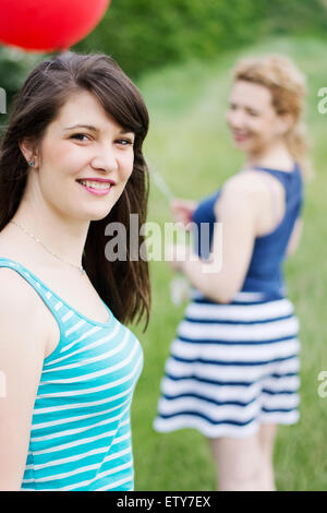 Closeup portrait of a young brunette girl walking behind her best friend, enjoying summer. Stock Photo