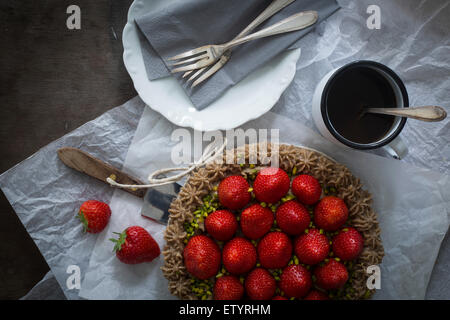 Strawberry tart with ribbon on wooden table with dishes Stock Photo