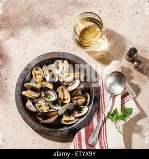 Shells vongole venus clams in metal dish and wine on stone background Stock Photo