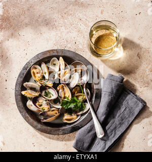 Shells vongole venus clams in metal dish and wine on stone background Stock Photo