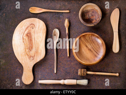 Set of olive wood cookware over brown metal background. Top view Stock Photo