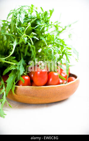 Green salad and red tomato raw on plate on neutral background detail with selective focus Stock Photo