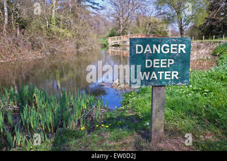 Danger deep water sign next to pond Stock Photo