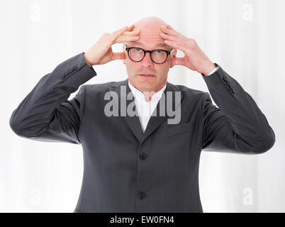 portrait of a bald-headed man in a suit with a headache Stock Photo