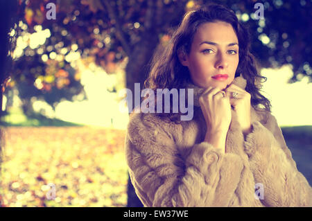 Autumn fashion portrait of young woman in fur coat in a UK park Stock Photo