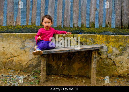 Two years old  girl sitting on rustic bench Stock Photo