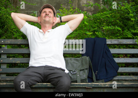 portrait of a man sitting on a bench in a park Stock Photo