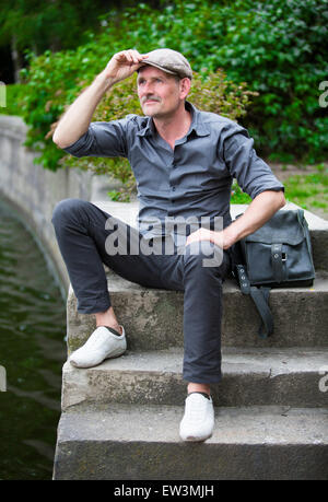 man sitting on stairs by the water Stock Photo