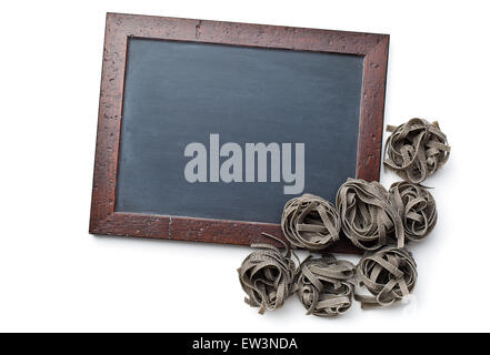 black tagliatelle pasta and chalkboard on white background Stock Photo