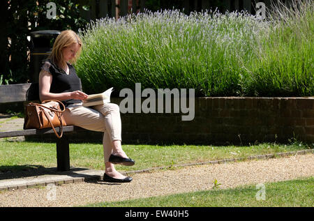 young woman reading a book in urban park Stock Photo