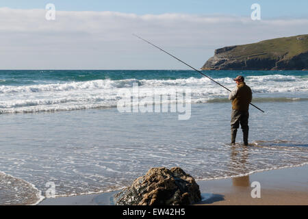 Fisherman sea fishing.  A man standing on the beach fishing on the Atlantic ocean coast at Trebarwith Strand,Cornwall, UK.  He is standing in the sea. Stock Photo