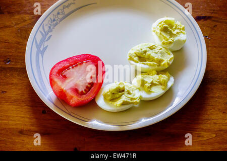 A half of a Roma tomato on a plate with deviled eggs. Stock Photo