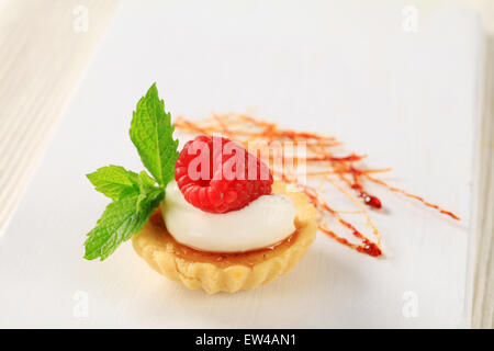 Creme brulee tartlet topped with cream and raspberry Stock Photo