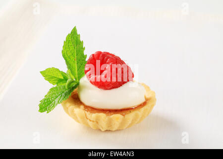 Creme brulee tartlet topped with cream and raspberry Stock Photo