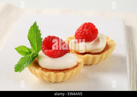 Creme brulee tartlets topped with cream and raspberry Stock Photo