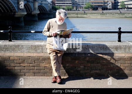 A senior citizen reading a newspaper on the South Bank, London Stock Photo