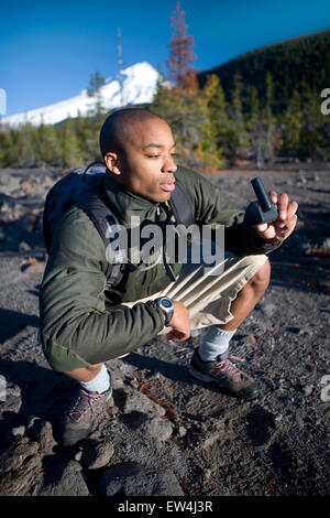 African American man Cupid Alexander uses gps while hiking near Mt. Hood in the Cascade Mountains Oregon. Stock Photo