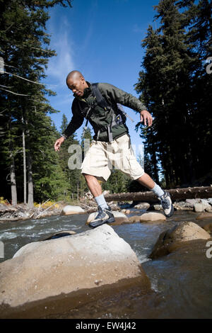 African American man Cupid Alexander jumps across creek in the Cascade Mountains Oregon. Stock Photo