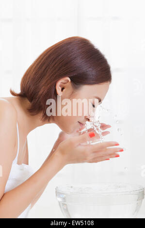 Young woman washing face with eyes closed Stock Photo