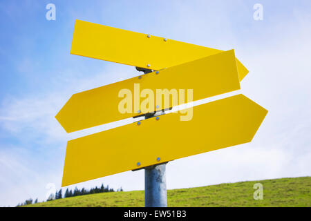 Three yellow empty arrow signs with free space and green meadow and blue sky Stock Photo