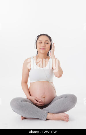 Pregnant woman listening to music on swing chair Stock Photo - Alamy