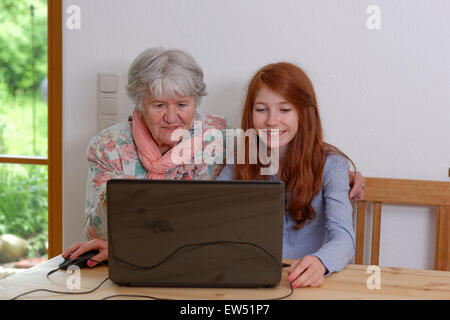Granddaughter and grandmother using laptop, Bavaria, Germany Stock Photo