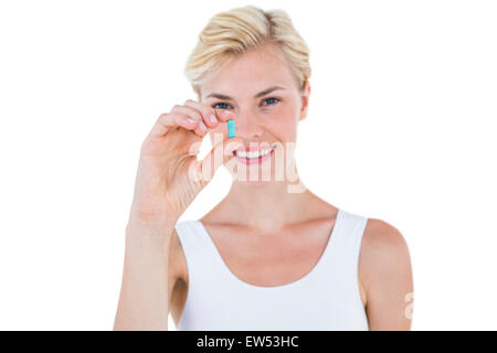 Smiling blonde woman holding blue pill Stock Photo
