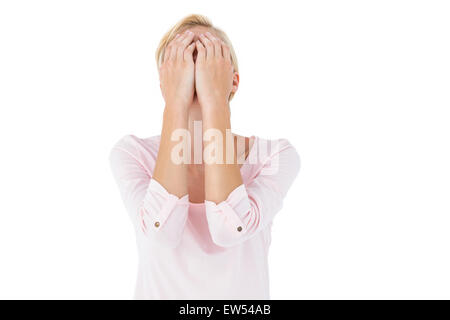 Nervous blonde woman covering her face Stock Photo