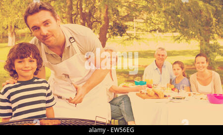 Father and son at barbecue grill with family having lunch in park Stock Photo