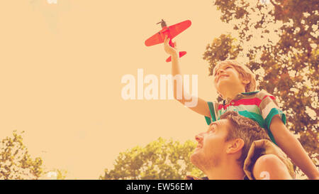 Boy with toy aeroplane sitting on fathers shoulders Stock Photo