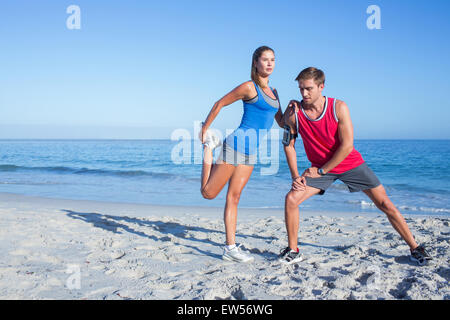 Happy couple stretching together beside the water Stock Photo