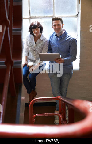 Two Businesspeople Having Informal Meeting On Office Stairs Stock Photo