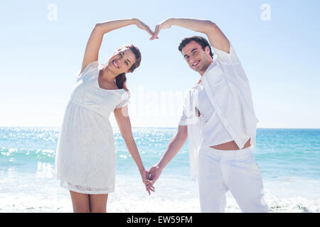 Happy couple forming heart shape with their hands Stock Photo
